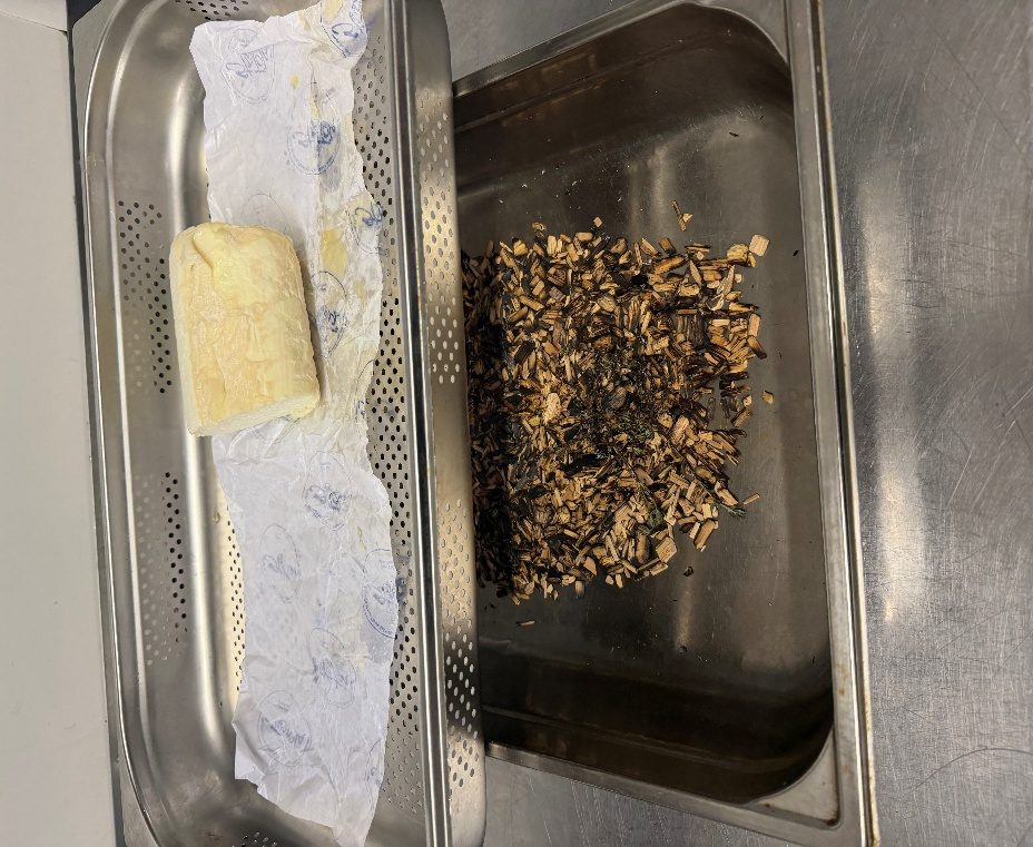 A St Tola log on its paper on a steamer tray beside a tray of hickory smoking chips
