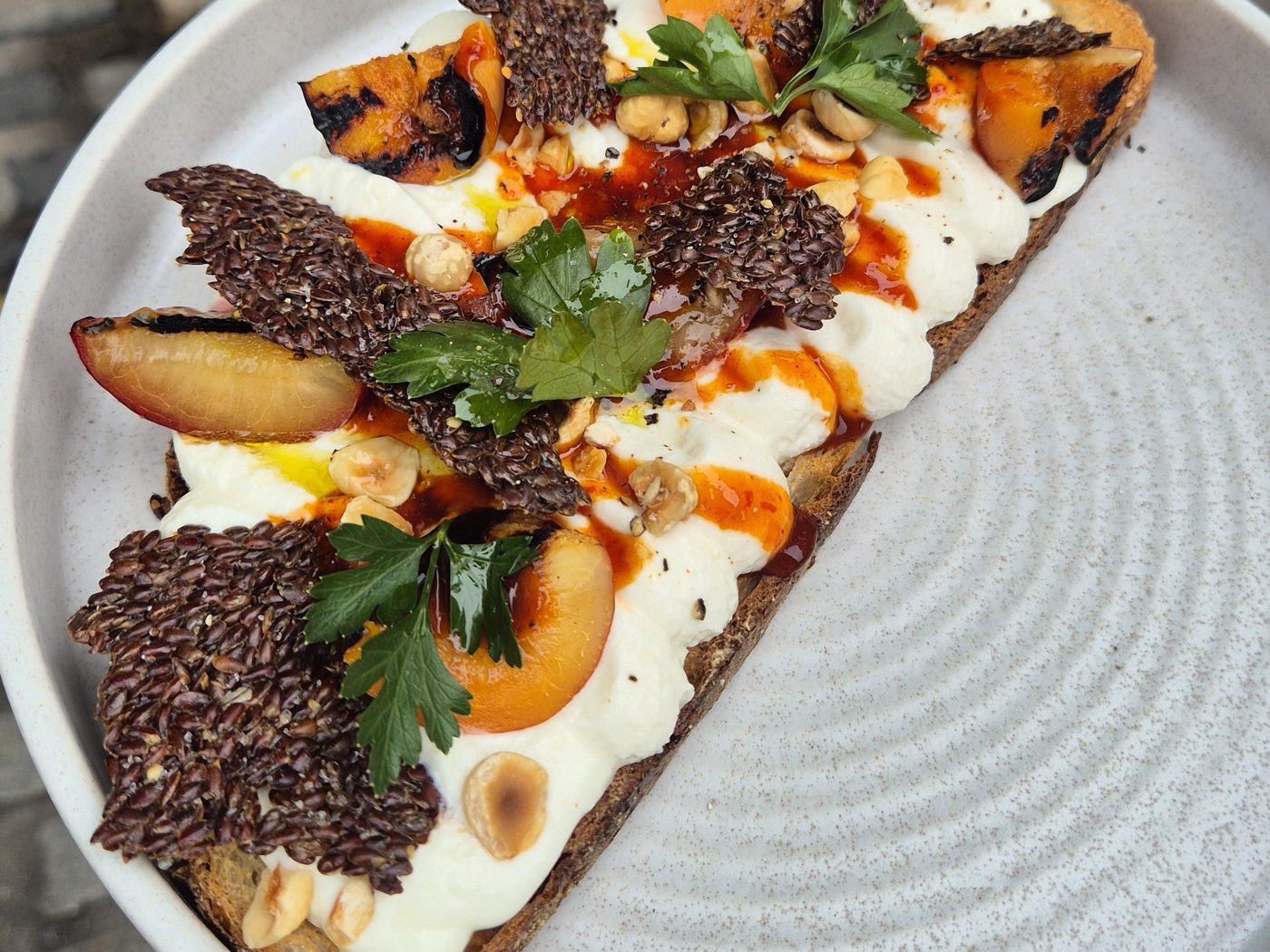 Whipped St Tola goat's curd with hot honey, hazelnuts, linseed cracker and grilled stone fruit on toasted sourdough